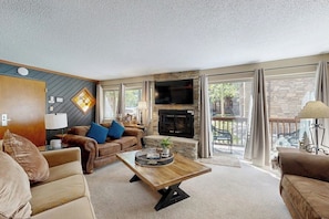 A living room with a fireplace, a sofa, a coffee table, and a television. - 1st-floor ski-in/out condo with fireplace, hot tubs, gym & grills (Breckenridge)