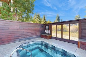 A hot tub area with a wooden deck, a glass enclosure, and a view of trees and sky. - 1st-floor ski-in/out condo with fireplace, hot tubs, gym & grills (Breckenridge)