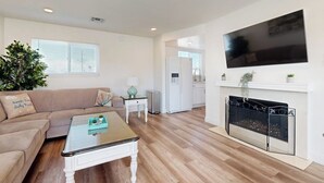Ein Wohnzimmer mit einer Couch, einem Couchtisch, einem Kamin und einem an der Wand befestigten Fernseher.