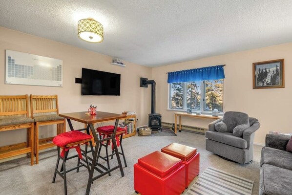 A cozy living room with a wooden bench, red chairs, a grey sofa, and a television. - Grandview ski-in/ski-out condo, 100 yards to the Four O'Clock Run (Breckenridge)