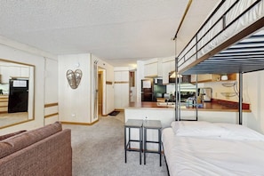 A compact hotel room with a bunk bed, kitchenette, and a small seating area. - Cozy ski-in/out condo with shared hot tub and pool, mountain views (Winter Park)