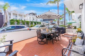 A patio with a table and chairs, a striped umbrella, and a barbecue grill.