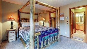 A four-poster bed with a patterned bedspread, wooden headboard, and two bedside lamps. - Beautiful and Secluded Mountain Home w/ Access to Shared Amenities (Breckenridge)