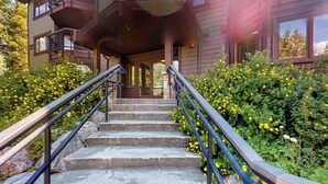 A wooden building with a staircase leading to a porch, surrounded by greenery and yellow flowers. - Beautiful and Secluded Mountain Home w/ Access to Shared Amenities (Breckenridge)