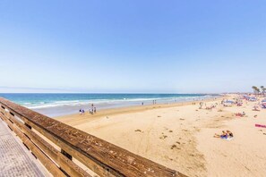Ein Strand mit einer Holzpromenade, Sand und Sonnenschirmen.