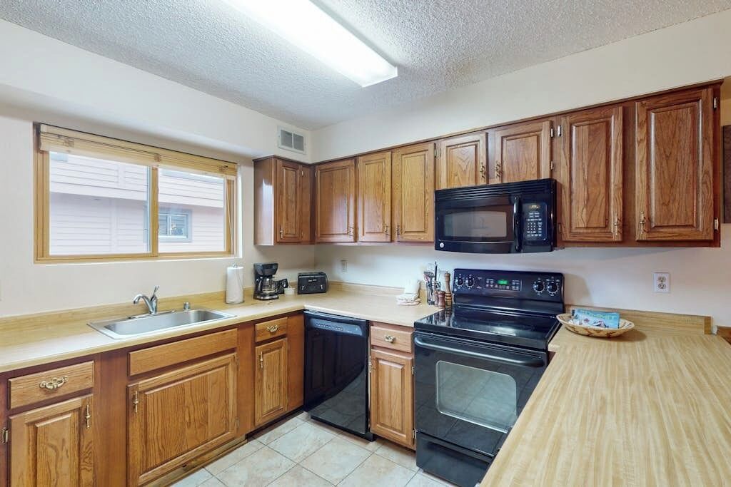 A kitchen with wooden cabinets, a microwave, a stove, and a dishwasher.