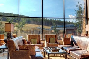 Ein großzügiger Raum mit Ledersofas und -sesseln, große Fenster mit Blick auf einen Wald und ein Gebäude mit der Aufschrift 'Independence'.