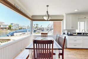 Ein Balkon mit Blick auf eine Marina, einem Esstisch mit Stühlen und einer Küchenzeile mit weißen Schränken.