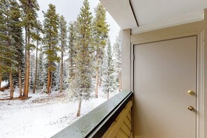 Schneebedeckte Landschaft mit hoch aufragenden Bäumen und einer Tür mit gelber Umrandung.