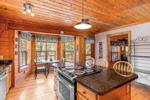 Ein Holzblockhaus-Interieur mit Küche, Essbereich und einem großen Fenster.