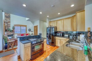 Eine moderne Küche mit Granitarbeitsplatten, Holzschränken, einem eingebauten Backofen und einem Edelstahl-Kühlschrank.