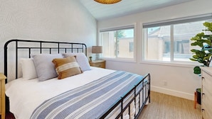Une chambre à coucher avec un lit, des tables de chevet, une fenêtre et une plante.