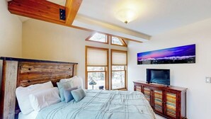 A bedroom with a bed, a TV, a wooden headboard, a window, and a painting on the wall. - Dog-friendly condo right in the center of town - walk to & from skiing (Breckenridge)