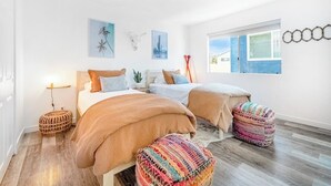 A bedroom with two beds, a window, and wall art. - Convenient dog-friendly condo with free WiFi - right up from the beach (San Clemente)