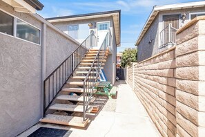 A narrow outdoor corridor with a staircase leading to a door marked '20'.