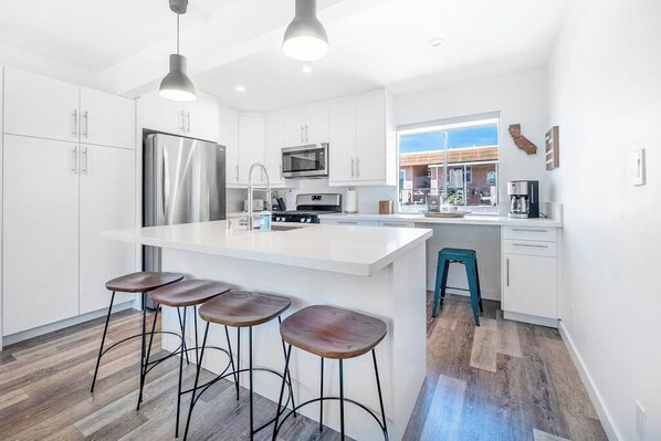 A modern kitchen with white cabinets, stainless steel appliances, and a central island with stools.