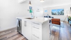 A modern kitchen with a central island, white cabinetry, and pendant lighting. - Convenient dog-friendly condo with free WiFi - right up from the beach (San Clemente)