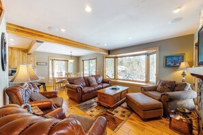 Ein geräumiges Wohnzimmer mit Ledersofas, einem Couchtisch und großen Fenstern.