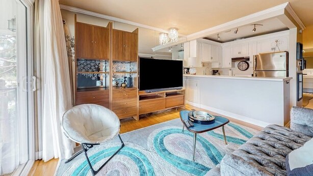 A modern living room with a flat-screen TV, a sofa, and a coffee table. - Glamorous, dog-friendly condo with pool, hot tub & W/D - snowbird-friendly (Newport Beach)