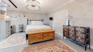 A bedroom with a bed, wooden chest, dresser, and a large chandelier. - Glamorous, dog-friendly condo with pool, hot tub & W/D - snowbird-friendly (Newport Beach)