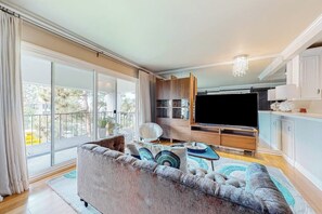 A modern living room with a sofa, TV, and wooden cabinets. - Glamorous, dog-friendly condo with pool, hot tub & W/D - snowbird-friendly (Newport Beach)