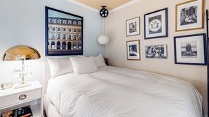 Une chambre avec un grand lit, une table de chevet avec une lampe et un mur orné de tableaux.