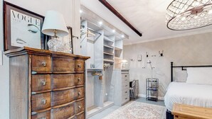 A bedroom with a bed, a dresser, a walk-in closet, and a chandelier. - Glamorous, dog-friendly condo with pool, hot tub & W/D - snowbird-friendly (Newport Beach)
