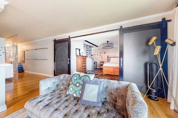 A spacious living room with a large sofa, a chandelier, and a sliding door leading to another room. - Glamorous, dog-friendly condo with pool, hot tub & W/D - snowbird-friendly (Newport Beach)