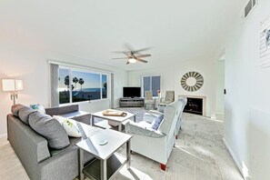 A modern living room with a sofa, coffee table, TV, and fireplace.