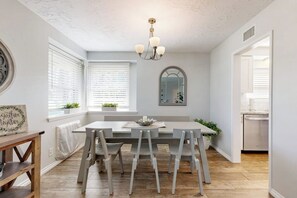 A dining area with a table, chairs, a chandelier, and a view into the kitchen. - Charming Orange Circle home with patio, grill, & game room - near Disneyland (Orange)