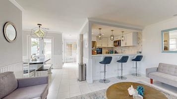 A modern living room with a sofa, a coffee table, and a kitchen area with bar stools.