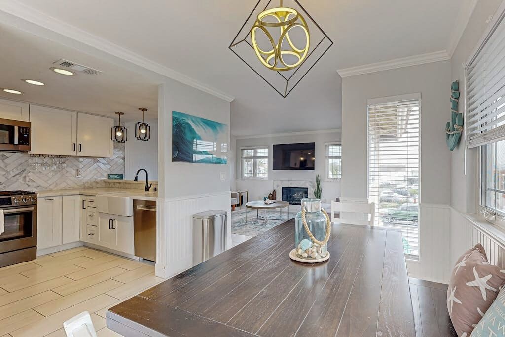 A modern kitchen with white cabinets, a marble backsplash, and a dark wooden island.