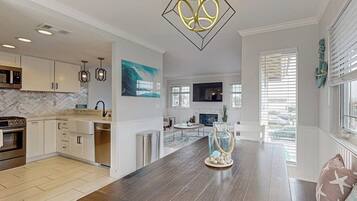 A modern kitchen with white cabinets, a marble backsplash, and a dark wooden island.