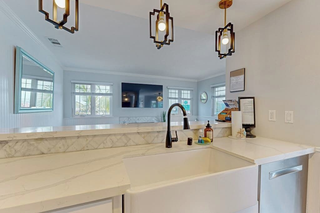 A modern kitchen with a white countertop, black faucet, and pendant lights.