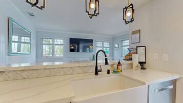 A modern kitchen with a white countertop, black faucet, and pendant lights.