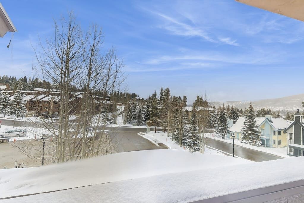 A residential area with snow-covered ground, houses, and trees.