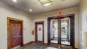 Un pasillo con puertas de madera, una puerta de cristal y una señal de salida.