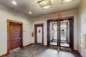 Un pasillo con puertas de madera, una puerta de cristal y una señal de salida.