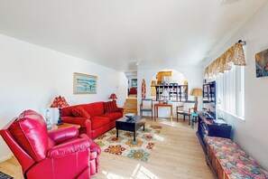 Una sala de estar con un sofá rojo, un sillón rojo, una mesa de centro y una estantería.