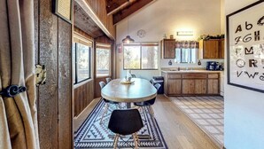 Una cocina rústica con armarios de madera, una mesa redonda y un tapete estampado.
