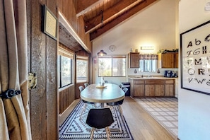 A rustic kitchen with wooden cabinets, a round dining table, and a patterned rug. - Dog-Friendly home with fireplace, washer/ dryer & deck - near shops & dining (Running Springs)