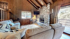 Un interior de madera con chimenea de piedra, un sofá y una televisión.
