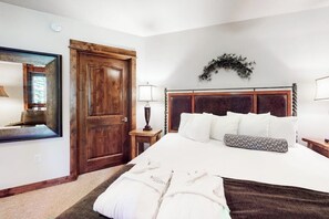 Ein Schlafzimmer mit Holztür, einem Bett mit weißer Bettwäsche, einem Spiegel und einer Wanddekoration.
