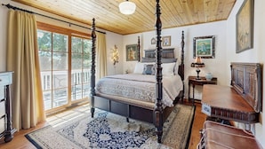 Un dormitorio con una cama con dosel, un ventanal con cortinas, techo de madera y vista al exterior.