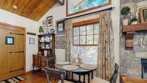 Un comedor con una mesa y sillas de madera, una chimenea y un ventanal con cortinas.