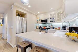 A modern kitchen with stainless steel appliances, a central island, and white cabinetry.