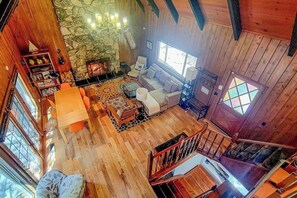 Un intérieur en bois avec un mur en pierre, une cheminée, un escalier et une vue sur l’extérieur.
