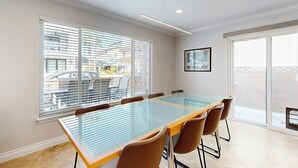 Una sala conferenze con un tavolo in vetro, sedie marroni e ampie finestre con tende.
