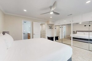 Ein Schlafzimmer mit einem großen Bett, einem Deckenventilator, einem Kleiderschrank und einem Spiegel.