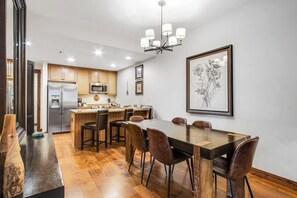 Eine moderne Küche mit Holzschränken, einem Edelstahlkühlschrank, einer Mikrowelle und einem Essbereich mit einem dunklen Holztisch und Stühlen.